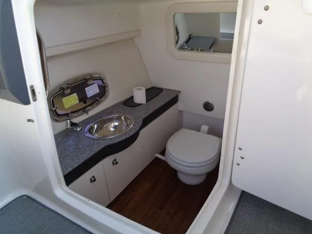 Slide: The Image of 2015 Chaparral 307 SSX boat interior bathroom with sink, toilet, and mirror. - 19