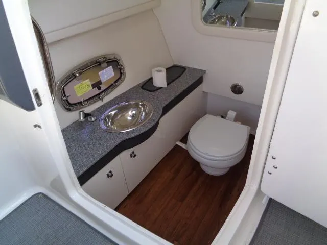 Slide: The Image of 2015 Chaparral 307 SSX boat bathroom with sink, toilet, and wood flooring. - 20