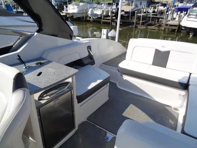 Slide: The Image of 2015 Chaparral 307 SSX boat interior with seating and kitchenette, docked at marina. - 24