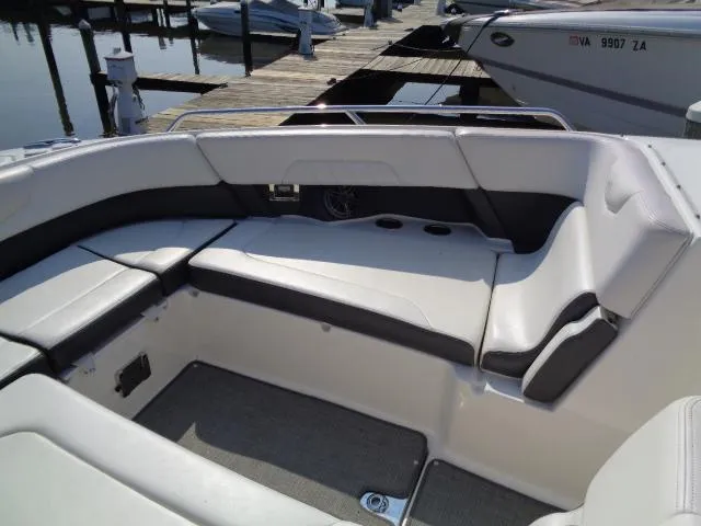 Slide: The Image of 2015 Chaparral 307 SSX boat interior with cushioned seating at a marina. - 8