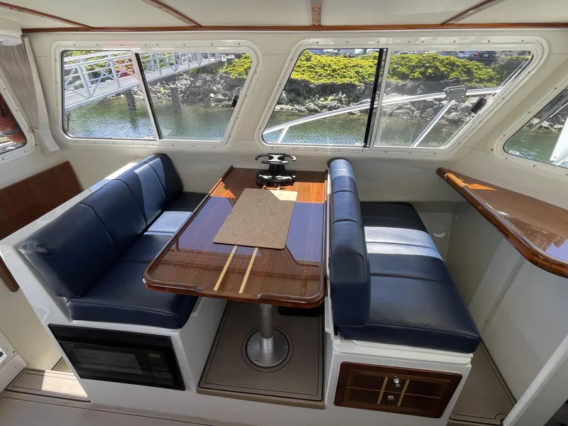 Slide: The Image of Interior of 2016 Lindell Ocean Roamer with blue seating and wooden table, overlooking water. - 16