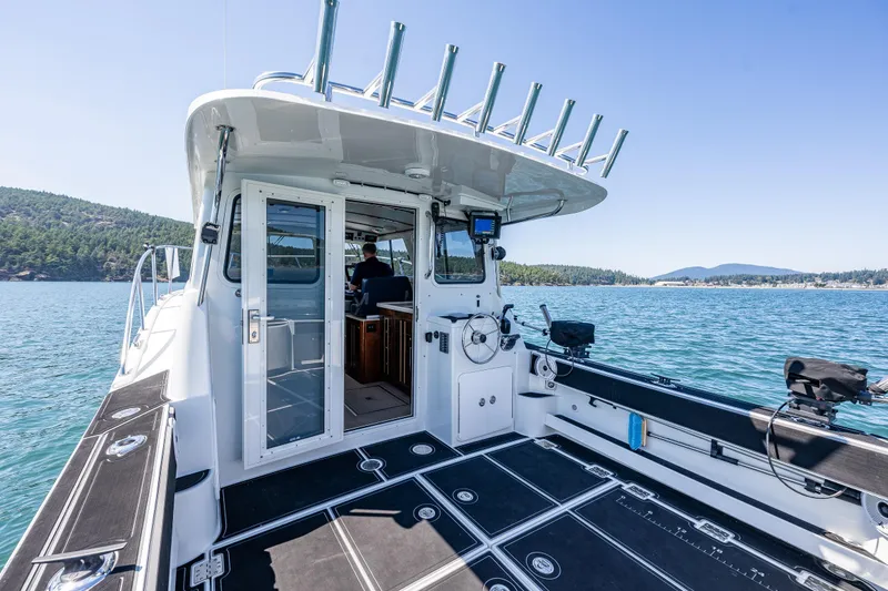 Slide: The Image of 2016 Lindell Ocean Roamer boat on scenic water with clear sky and lush landscape. - 22