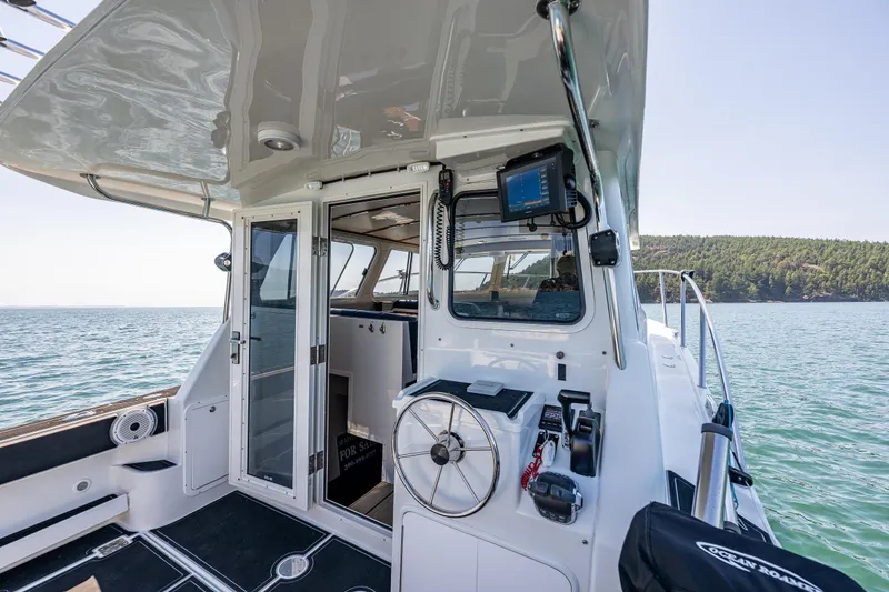 Slide: The Image of 2016 Lindell Ocean Roamer boat interior with steering wheel, navigation equipment, and ocean view. - 25