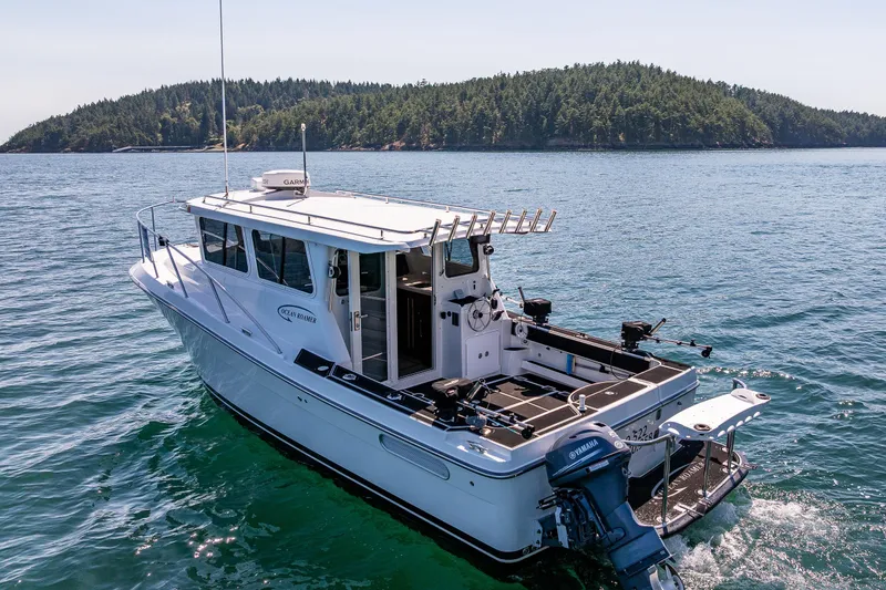 Slide: The Image of 2016 Lindell Ocean Roamer boat cruising on scenic blue waters near a forested island. - 36