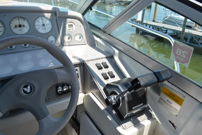 Slide: The Image of 1998 Formula 31 PC boat cockpit with steering wheel and control panel, docked by the water. - 13