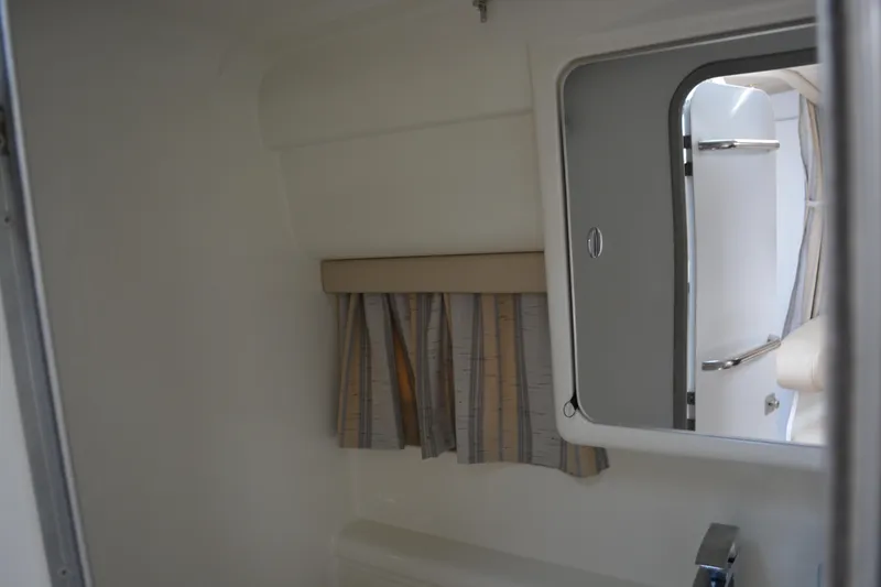 Slide: The Image of Interior of a 1998 Formula 31 PC boat, featuring a compact bathroom with a mirror and curtain. - 31