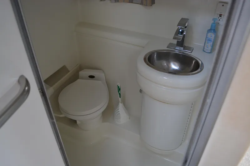 Slide: The Image of Compact bathroom in a 1998 Formula 31 PC boat, featuring a toilet and sink. - 32