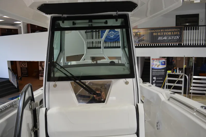 Slide: The Image of 2026 Blackfin 272 CC boat interior with windshield and wipers in showroom setting. - 19