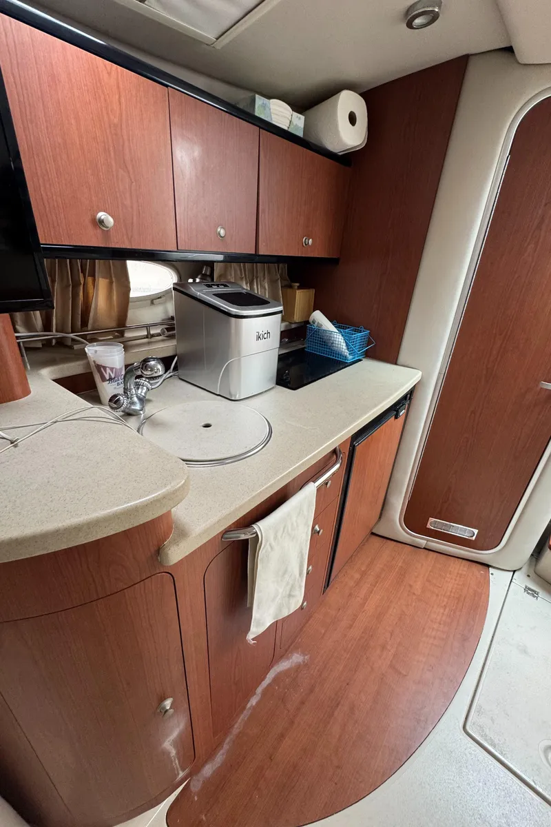 Slide: The Image of 2004 Chaparral 330 Signature yacht interior with kitchenette, featuring wood cabinets and modern appliances. - 20