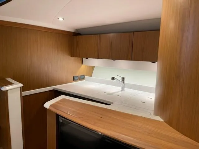 Slide: The Image of 2022 Tiara Yachts 39 Open interior kitchen with modern wood cabinetry and sleek countertops. - 8