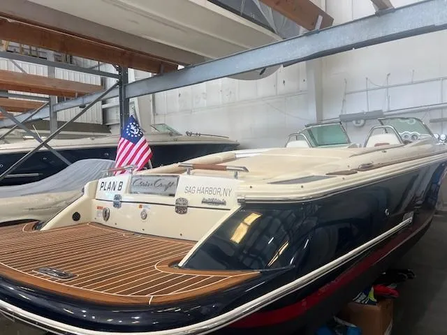 Slide: The Image of 2020 Chris-Craft Launch 27 boat in storage, featuring teak deck and American flag. - 3