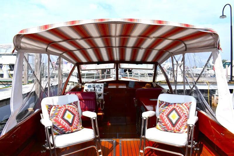 Slide: The Image of 1960 Chris-Craft Sea Skiff interior with striped canopy and colorful cushions at a marina. - 5