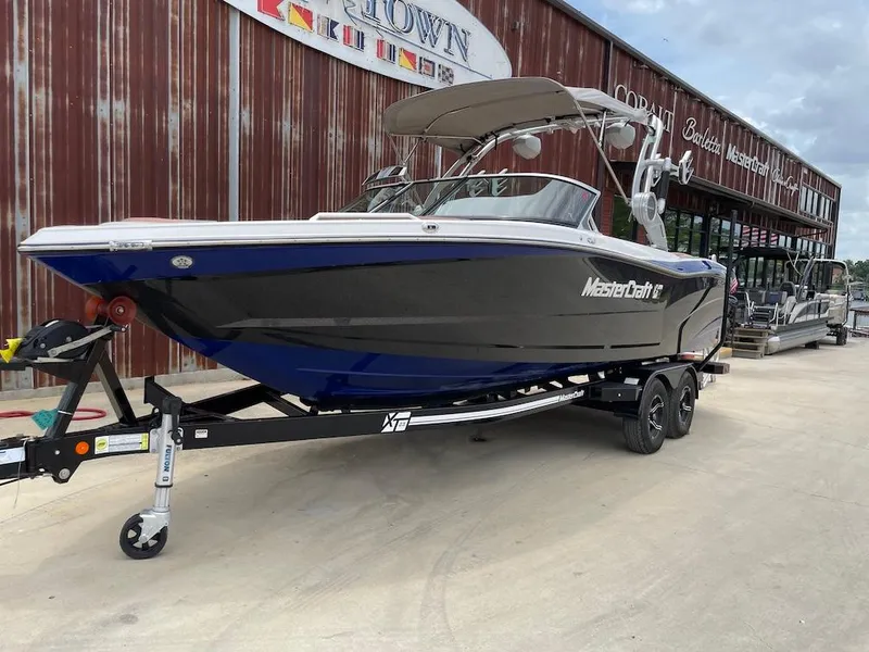 Slide: The Image of 2019 MasterCraft XT23 boat on trailer, parked outside a dealership. - 1