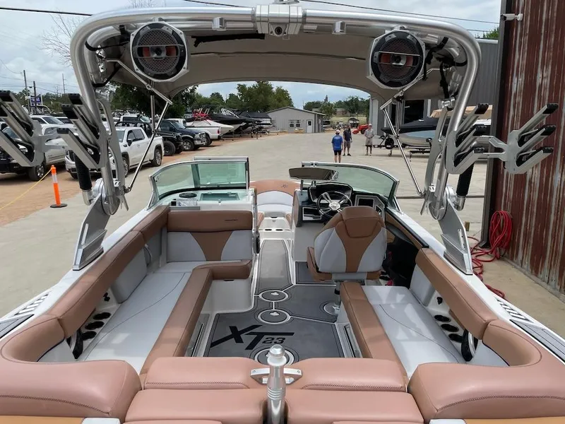 Slide: The Image of 2019 MasterCraft XT23 boat interior with seating, speakers, and steering wheel, parked outdoors. - 5