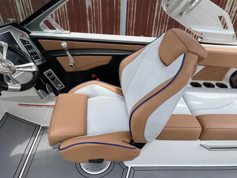 Slide: The Image of 2019 MasterCraft XT23 boat interior with tan and white seating, steering wheel, and dashboard controls. - 8