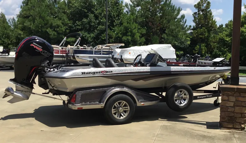 Slide: The Image of 2023 Ranger Z518 boat on trailer, parked outdoors with trees in background. - 11