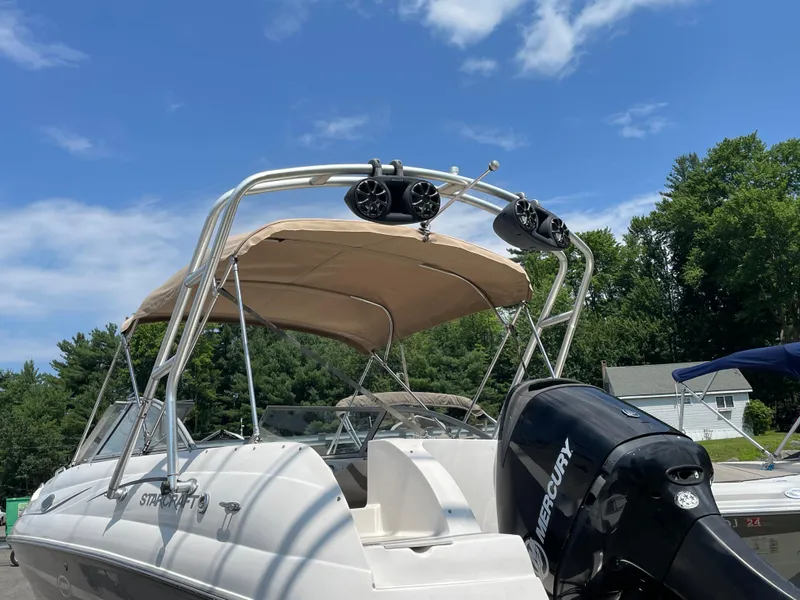 Slide: The Image of 2007 Starcraft 2410 OB Limited boat with Mercury engine, beige canopy, and speakers, under blue sky. - 4