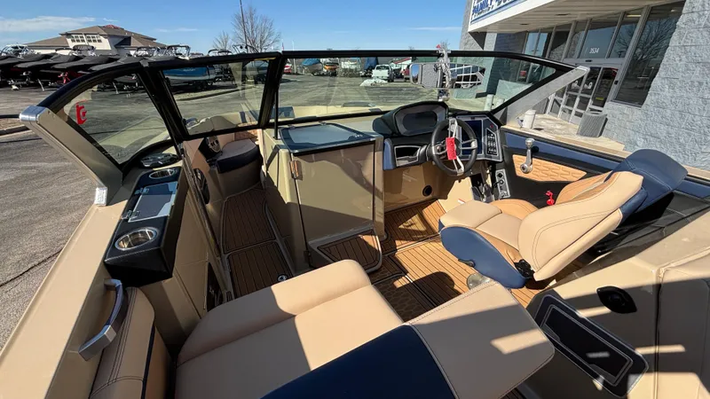 Slide: The Image of 2022 MasterCraft X26 boat interior with tan and navy seating, modern dashboard, and open cockpit. - 15