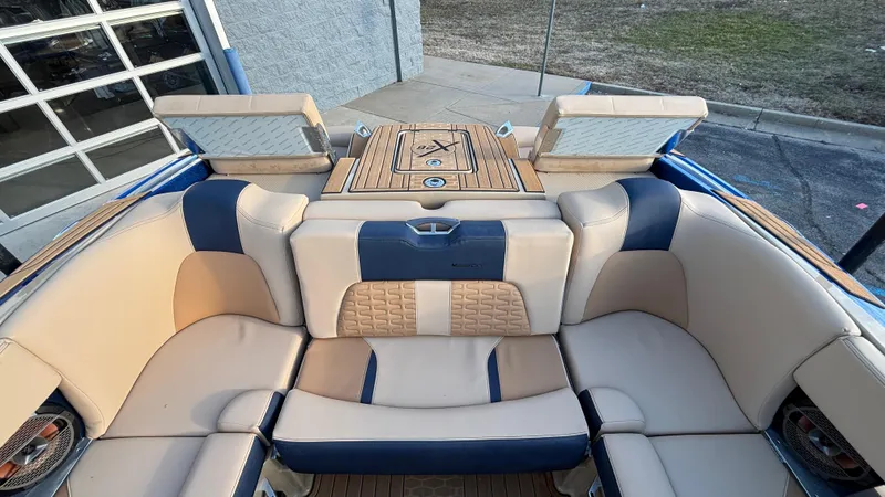 Slide: The Image of 2022 MasterCraft X26 boat interior with beige and blue seating, featuring a teak deck. - 20
