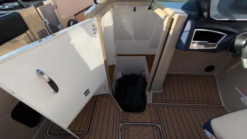 Slide: The Image of 2022 MasterCraft X26 boat interior storage compartment with open door and wooden flooring. - 28