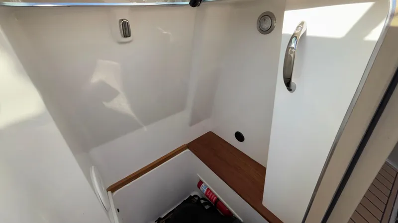 Slide: The Image of 2022 MasterCraft X26 interior storage compartment with wooden accents and safety equipment. - 29