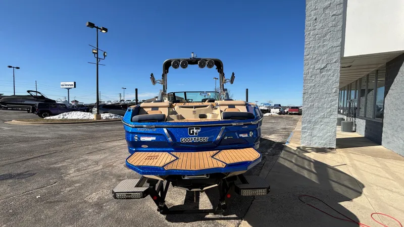 Slide: The Image of 2022 MasterCraft X26 boat in blue, parked outdoors on a sunny day. - 5
