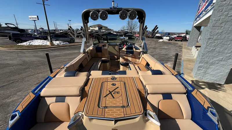Slide: The Image of 2022 MasterCraft X26 boat with luxurious seating and sleek design in a dealership lot. - 7
