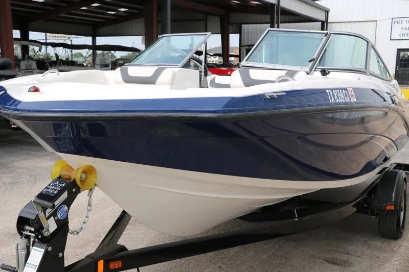 Slide: The Image of 2014 Yamaha Boats SX190 on trailer, blue and white exterior, parked in covered area. - 6