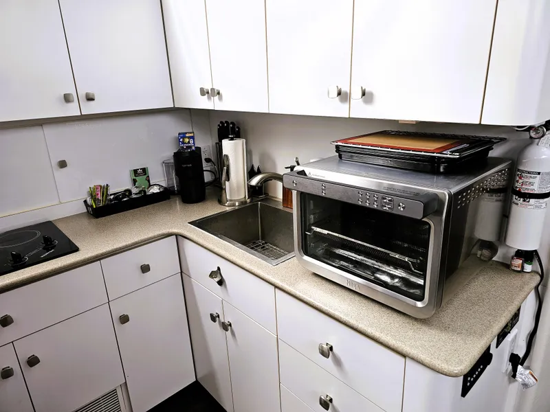 Slide: The Image of Compact kitchen in a 1995 Silverton 46 yacht with modern appliances and white cabinetry. - 14