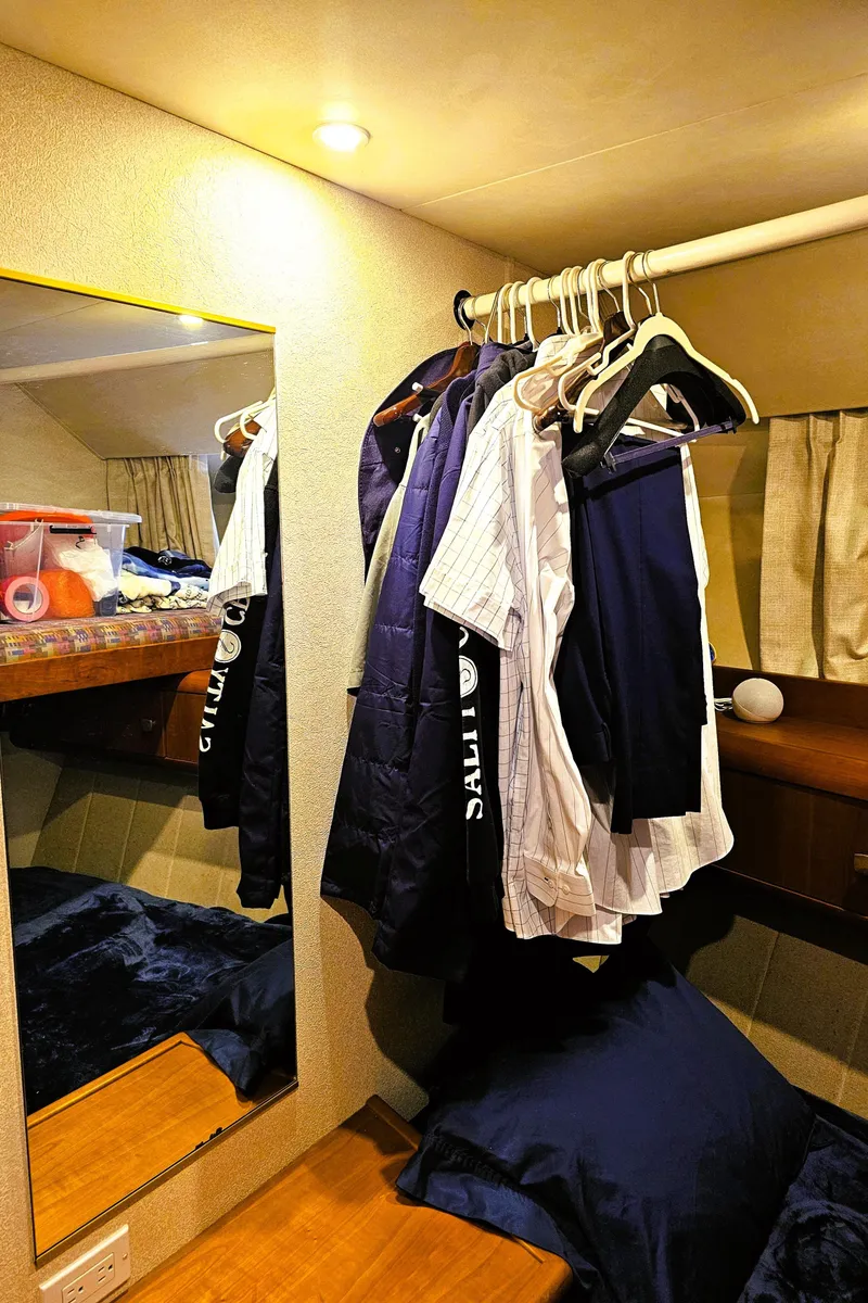 Slide: The Image of Clothes hanging in a 1995 Silverton 46 yacht cabin with mirror and bedding. - 19