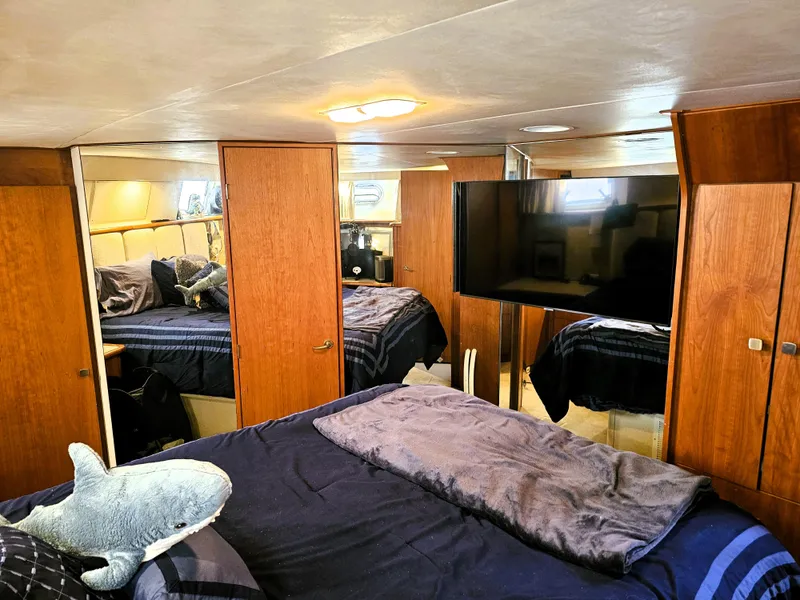 Slide: The Image of Luxurious 1995 Silverton 46 yacht bedroom with plush bedding and wooden cabinetry. - 23