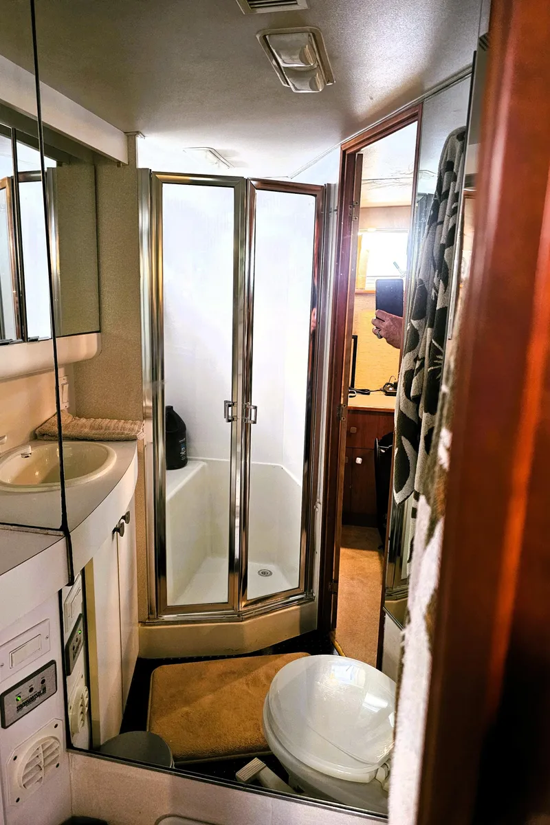 Slide: The Image of Bathroom interior of a 1995 Silverton 46 yacht, featuring a shower, sink, and toilet. - 26