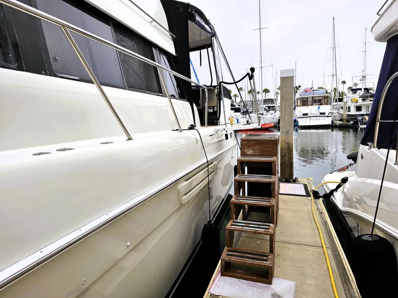 Slide: The Image of 1995 Silverton 46 yacht docked at marina with wooden steps for boarding. - 7