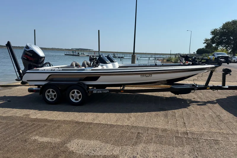 Slide: The Image of 2004 Skeeter ZX250 boat on trailer by a lakeside dock. - 18