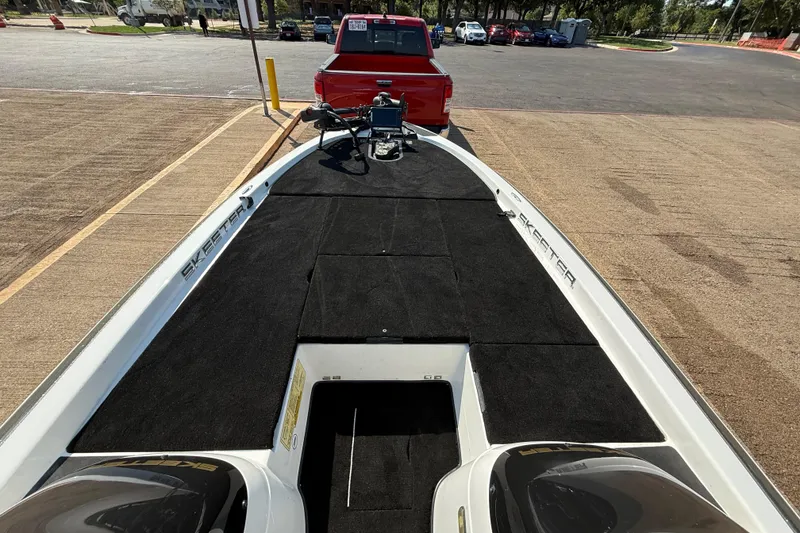 Slide: The Image of 2004 Skeeter ZX250 boat on trailer, parked behind a red truck in a parking lot. - 40