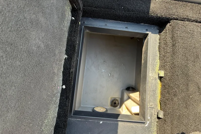 Slide: The Image of Open storage compartment in 2004 Skeeter ZX250 boat, featuring black carpeted interior. - 62