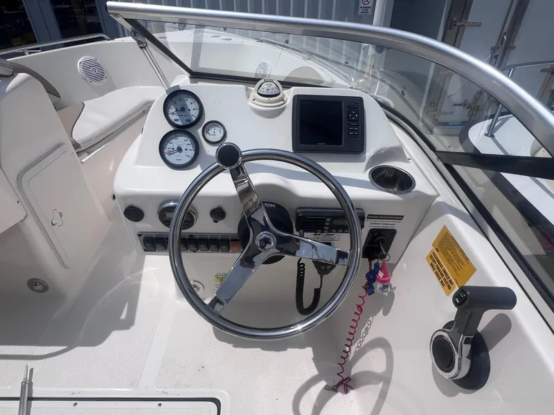 Slide: The Image of 2016 Key West 186 Dual Console boat dashboard with steering wheel and gauges. - 13