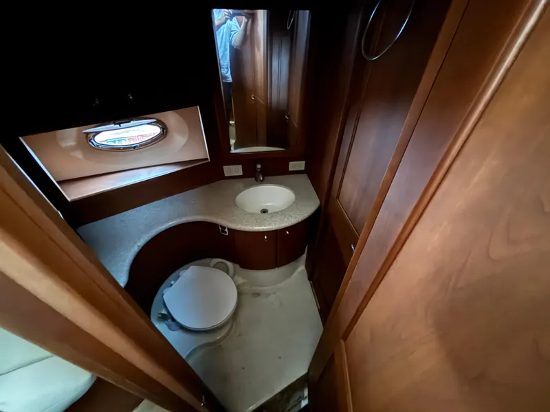 Slide: The Image of 2004 Silverton 35 Motor Yacht bathroom with wooden cabinetry and porthole window. - 13