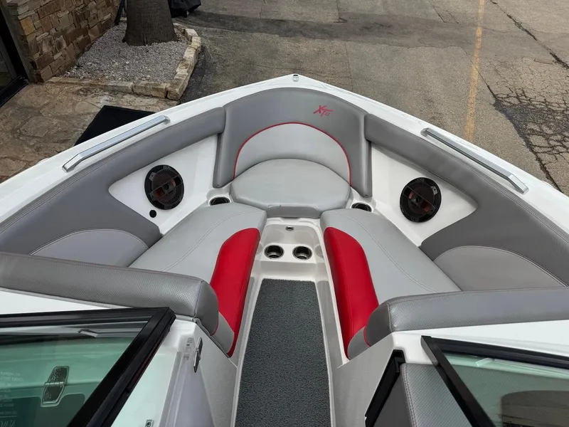Slide: The Image of 2018 MasterCraft XT23 boat interior with gray and red seating, speakers, and cup holders. - 11