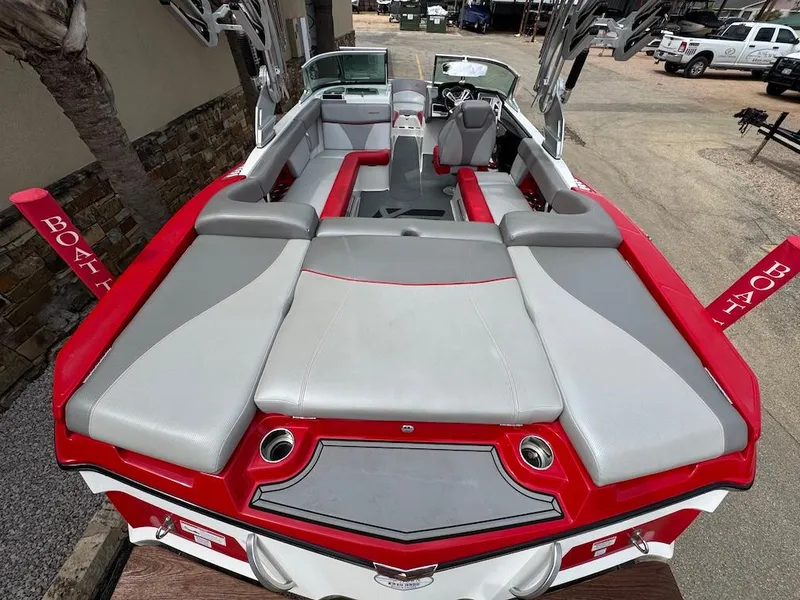 Slide: The Image of 2018 MasterCraft XT23 boat with red and gray seating, parked outdoors. - 5