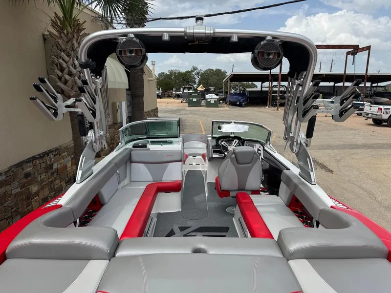 Slide: The Image of 2018 MasterCraft XT23 boat interior with red and gray seating, wakeboard racks, and speakers. - 6