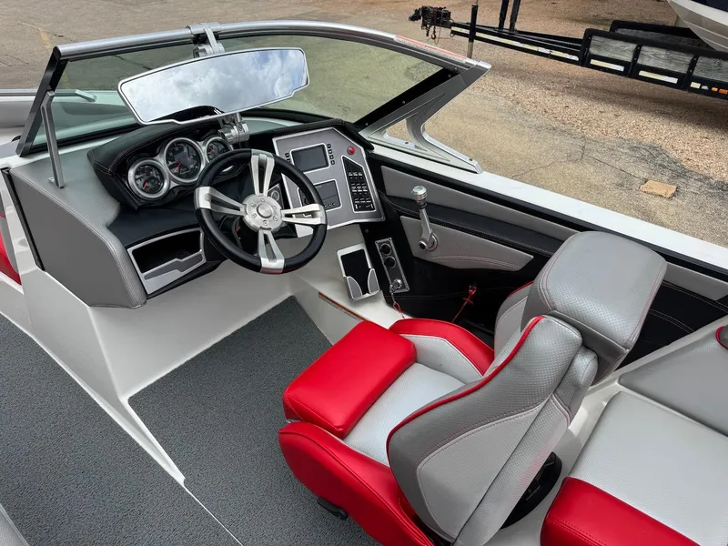 Slide: The Image of 2018 MasterCraft XT23 boat interior with red and gray seating, modern dashboard, and steering wheel. - 9