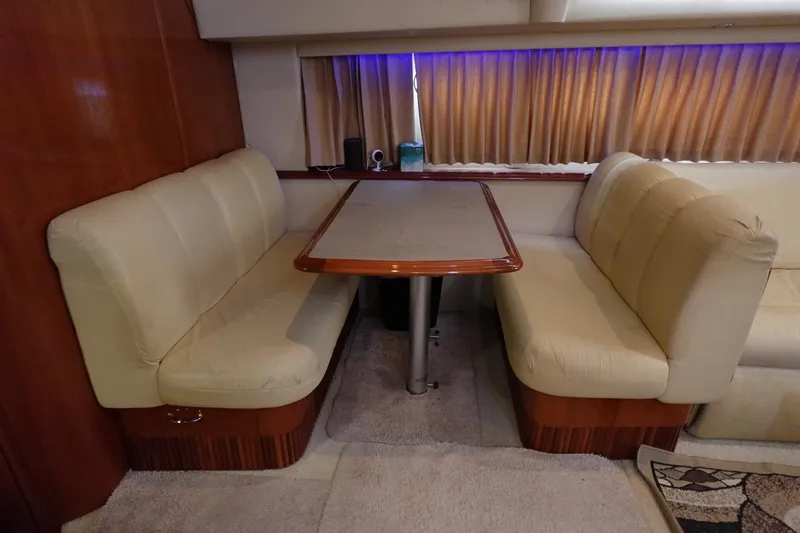 Slide: The Image of 2004 Carver 396 Aft Cabin MY interior with beige seating and wooden table. - 10