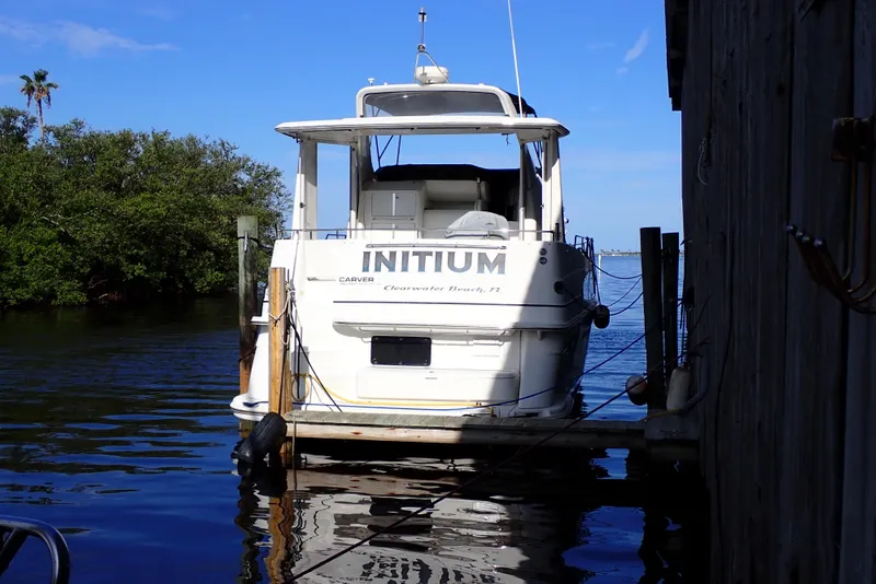 Slide: The Image of 2004 Carver 396 Aft Cabin MY docked, rear view, with clear blue sky and water. - 2
