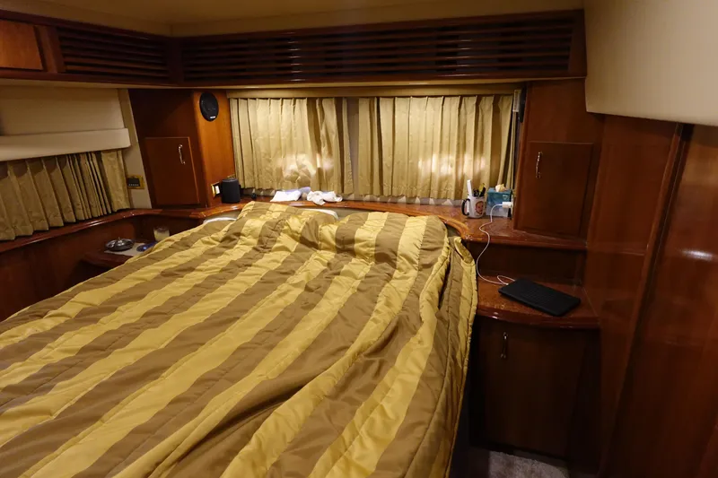 Slide: The Image of Luxurious 2004 Carver 396 Aft Cabin MY bedroom with striped bedding and wooden cabinetry. - 25