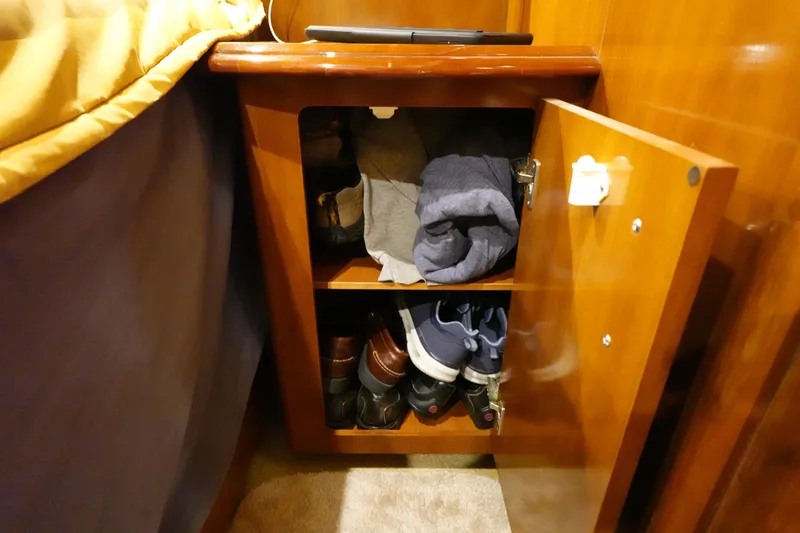 Slide: The Image of Open wooden cabinet with clothes and shoes inside, on a 2004 Carver 396 Aft Cabin MY. - 42