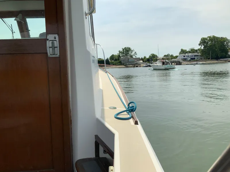 Slide: The Image of 1986 Cape Dory 26 Fly on calm water near shoreline with houses in background. - 5