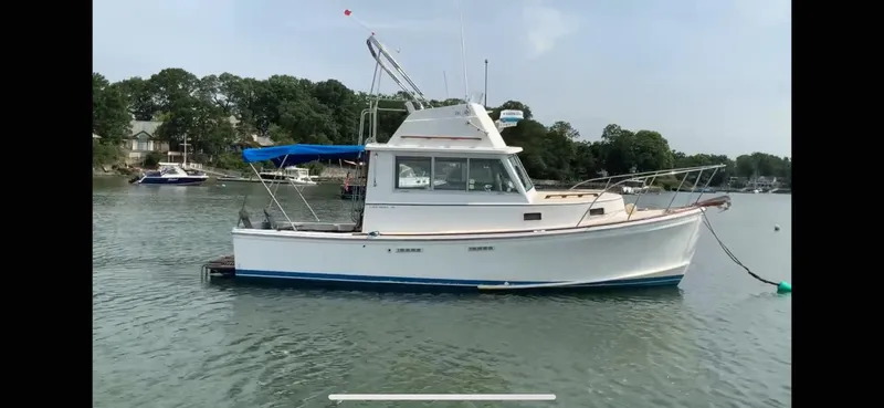 Slide: The Image of 1986 Cape Dory 26 Fly boat anchored on calm water with trees in the background. - 6