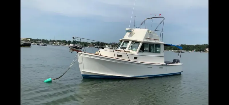 Slide: The Image of 1986 Cape Dory 26 Fly boat anchored on calm water, clear sky background. - 8
