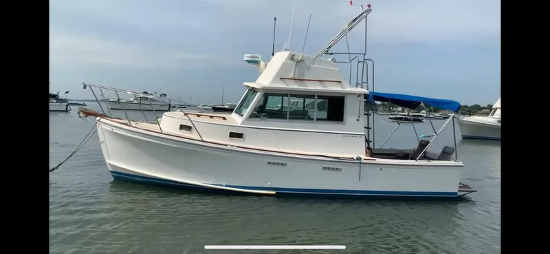 Slide: The Image of 1986 Cape Dory 26 Fly boat on calm water, featuring a classic design and blue canopy. - 9